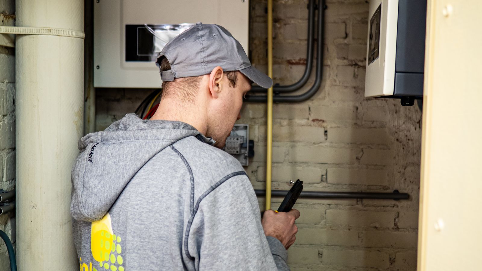 Technicien contrôlant un onduleur solaire et son coffret de stockage dans un local technique