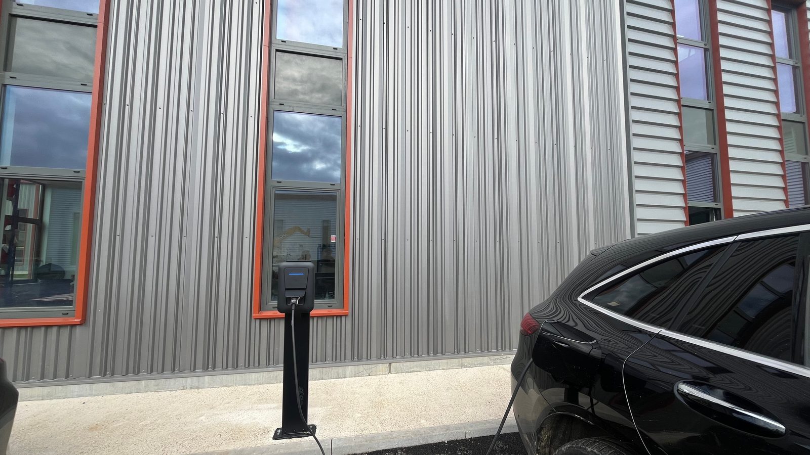 Borne de recharge sur pied et véhicule électrique branché sur un parking d'entreprise